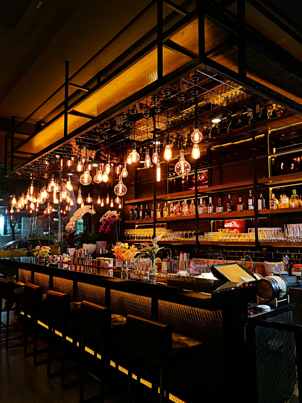 Warm beleuchtete Bar mit Glühbirnen und Spirituosenregal bei MELLA'S